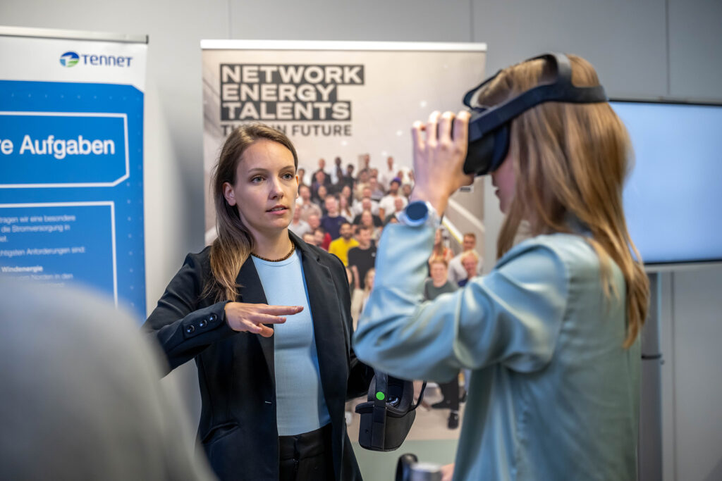 Eine Frau erklärt einer Besucherin eine VR-Brille am Stand von Network Energy Talents.