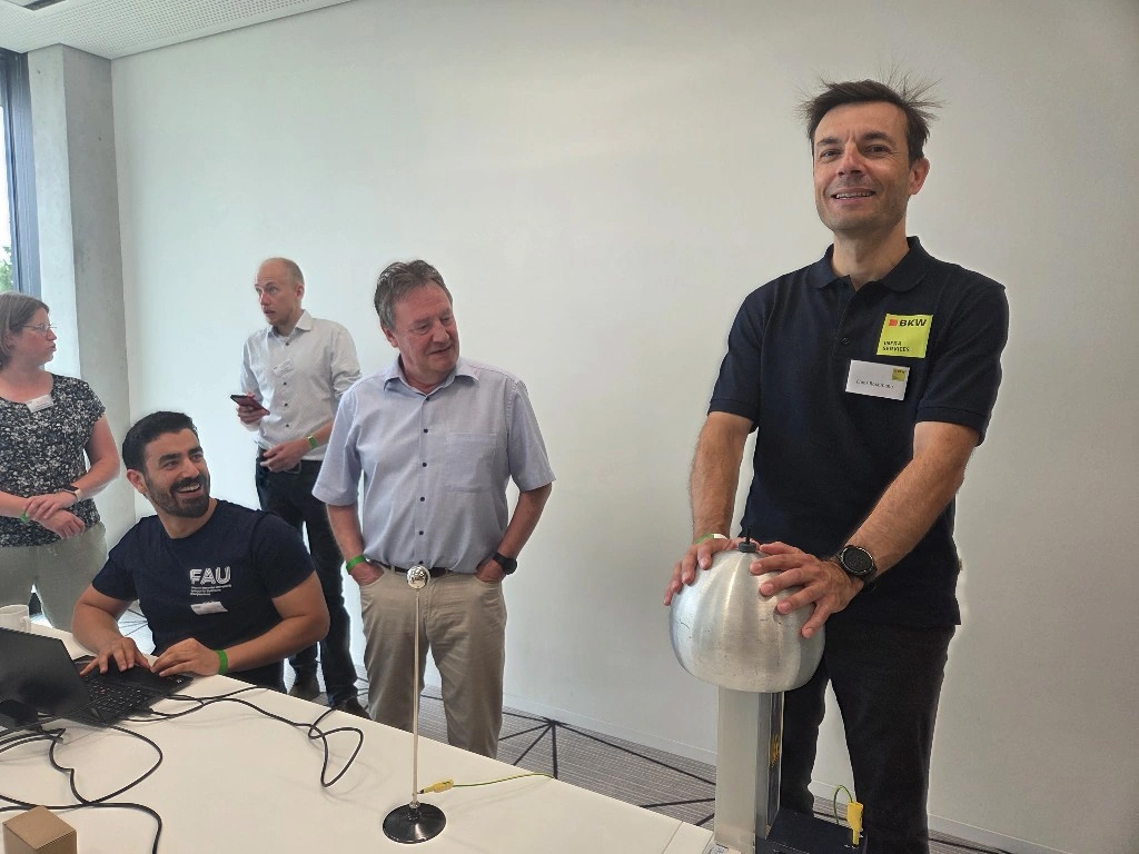 Mehrere Personen beobachten ein Experiment mit einer Metallkugel.