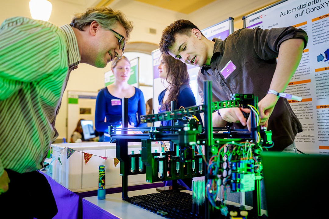 Studierende präsentieren ein automatisiertes Modell bei einer Hochschulveranstaltung.