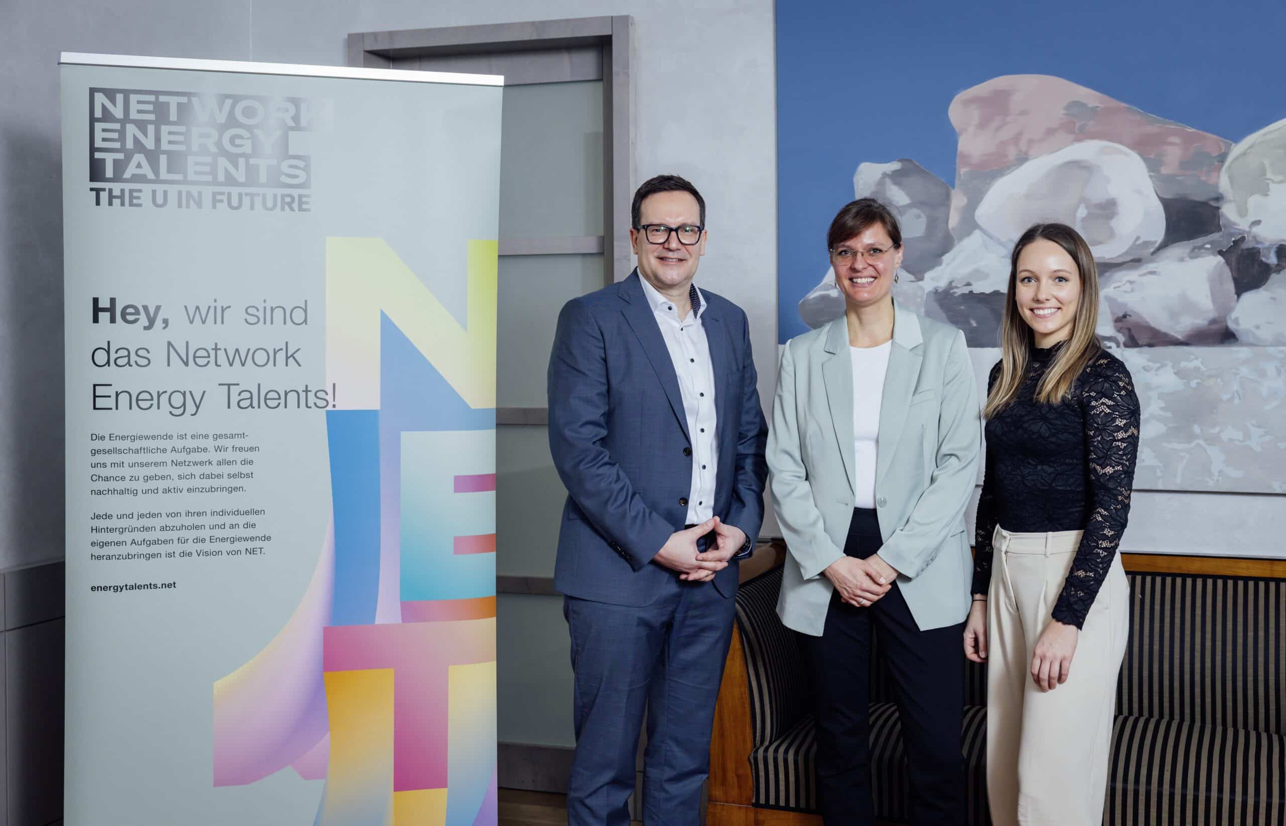 Drei Personen stehen neben einem Network Energy Talents-Banner.